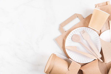 Eco-friendly disposable utensils made of bamboo wood and paper on white marble background