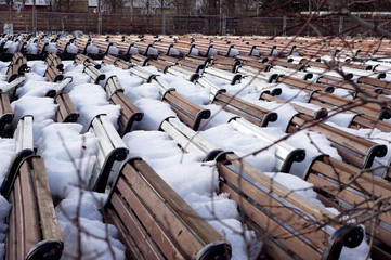 Park benches stored and covered with show in early spring