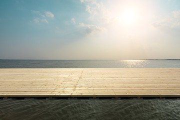 Fototapeta na wymiar Wooden floor platform and blue sea with sky background