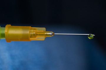 macro view of a hypodemic needle with a drop of drug solution on his peak