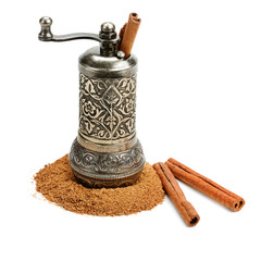 Rolled bark and cinnamon powder and hand mill isolated on white background.