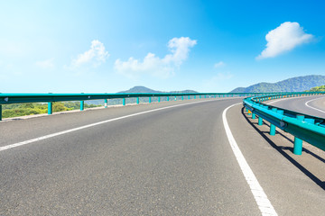 Fototapeta premium Empty asphalt road and mountains with blue sky on a sunny day