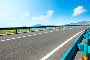 Fototapeta premium Empty asphalt road and mountains with blue sky on a sunny day