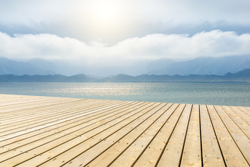 Fototapeta premium Wooden floor platform and lake with sky background