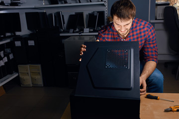 cheerful guy opening the system unit at workplce, close up photo, computer programmer is keen on...
