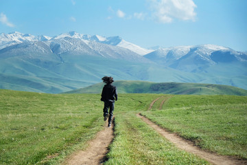 Fototapeta na wymiar a man in black clothes running along the country road toward mountains