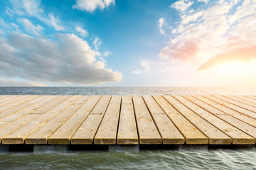 Wooden floor platform and blue sea with sky background