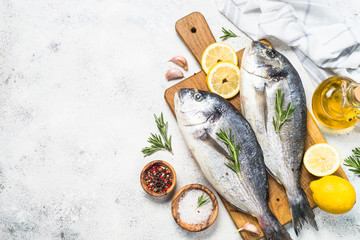 Raw dorado fish on cutting board on the table.