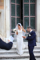 Happy just married couple under a rice rain. 