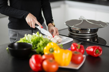 The girl cuts vegetables in the kitchen, close-up