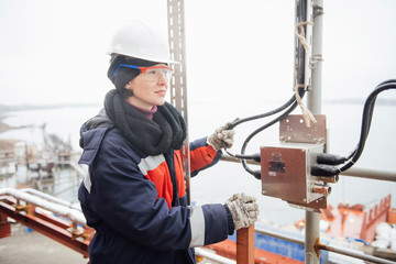 A woman in overalls, protective helmet and goggles working