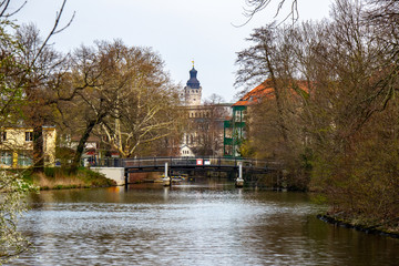 View of a bridge over the river "Weisse Elster" in Leipzig with trees and the New Town Hall in the background