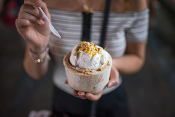 Girl tasting a coconut ice cream in a night market during a vacation in Thailand