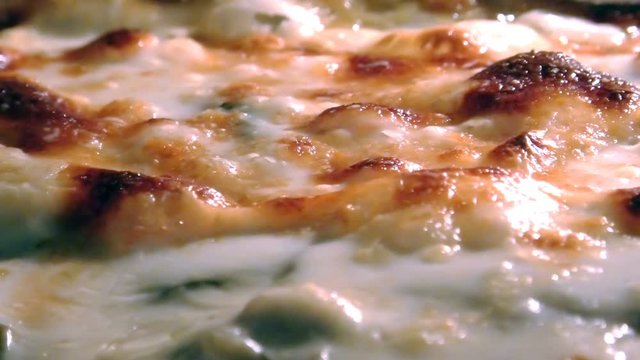 baking Moussaka with vegetables and bechamel boiling in a oven. Close up view of cheese bubbles. Traditional greek dish.