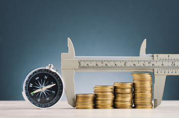 saving money concept,vernier caliper and stacking coins on wooden desk over beautiful reverberation...