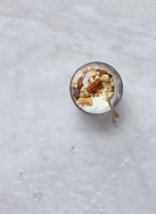 Granola with yogurt, honey and chocolate bars on marble table with copy space