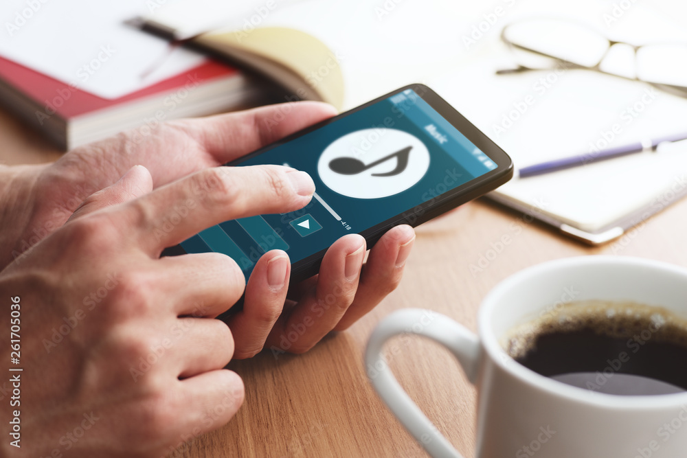 Aufkleber Closeup of male hands touching smartphone screen for listening music at table. Digital music player app on smartphone screen.