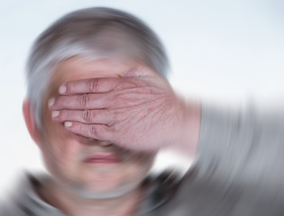 An elderly man is disoriented, he is dizzy, he holds his hand over his eyes. Concept health.