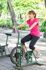 Obraz premium Female exercise with cycling machine at public park.