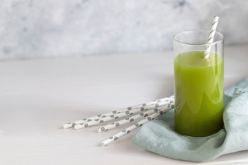 Freshly blended green smoothie in in a glass with straws on the table. Detox vegetable juice. Healthy lifestyle concept. Raw drink for vegan diet.