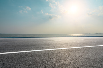 Fototapeta premium Empty asphalt road and blue sea with sky background