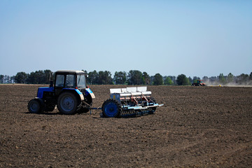Tractor with the seeder before the cereal planting works. Spring agricultural works. Arable land...