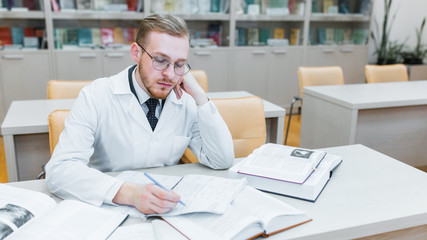 background a medical student for textbooks. The study of surgery by a man in a tie in the library
