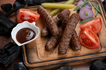 Close-up of bbq cevapcici or skinless beef sausages on a wooden serving board, selective focus