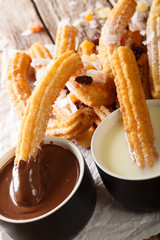 Deep-fried sweet churros served with hot chocolate and condensed milk close-up. vertical