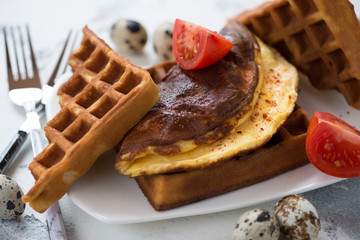 Close-up of belgian waffles served with quail eggs omelette, selective focus
