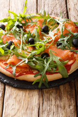 Homemade Italian pizza with salted salmon, fresh arugula, olives and cheese closeup. vertical