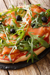 Delicious pizza with salted salmon, arugula, olives and cheese closeup. vertical