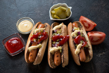 Freshly made hot-dogs over dark brown stone background, horizontal shot, elevated view