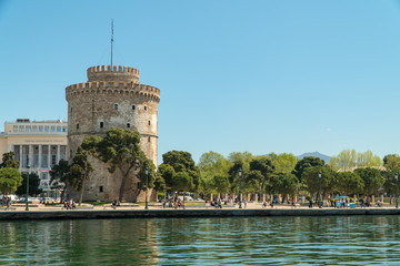 Thessaloniki / Greece 11 April 2019  the blue sea and the  white tower of thessaloniki city's symbol and landmark ,beautiful sunny day after long time of rain and clouds great opportunity for a walk. - obrazy, fototapety, plakaty
