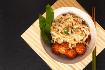 Asian Food concept homemade oriental egg noodles and spicy meatballs in ceramic bowl on black background