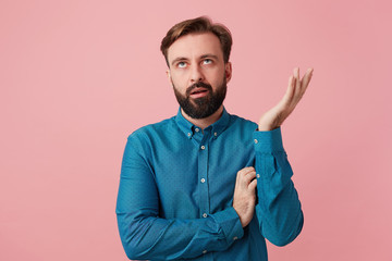 Indoor shot of a man looks irritated dissatisfied, raised a hand depict if he hears something obvious once again, someone voiced his opinion about his shortcomings, looking upward discontent