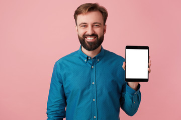 Representative, personable man with beard looking camera with wide toothy smile, holds tablet with...