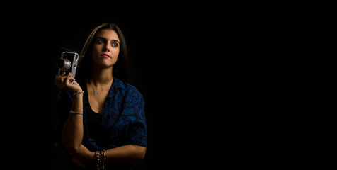 girl posing with an old camera reflex, black background and copy space