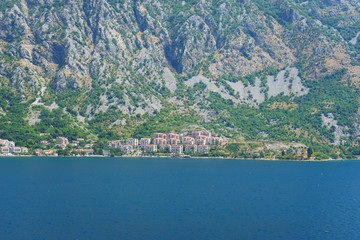 Mediterranean seascape: cozy town with old stone houses red roofs and mountains background.