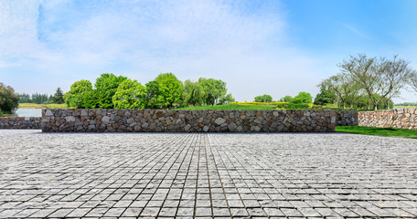 Rough square stone floor and green woods with sky background - Powered by Adobe