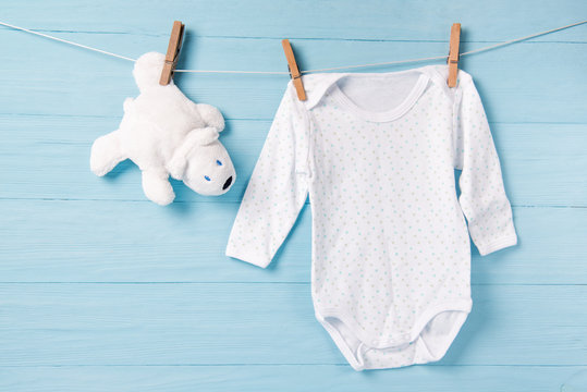 Baby boy clothes and white bear toy on a clothesline, blue background