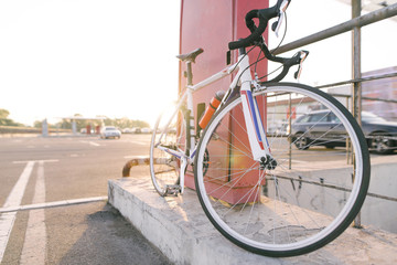 Beautiful bicycle is standing in the street on the background of parking for cars in the sunset. Ecological transport. Sports concept. Bike and copyspace