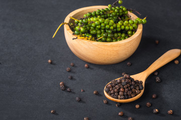 Close-up of ground black pepper in wooden spoon on black table