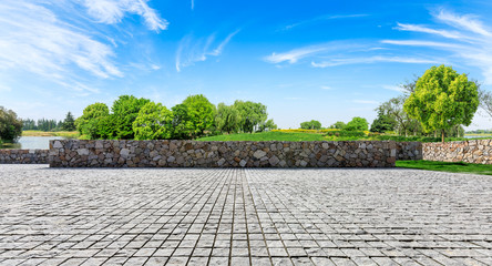 Rough square stone floor and green woods with sky background