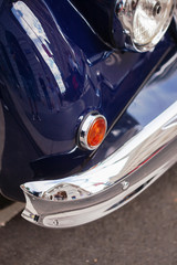 Fototapeta na wymiar Front part with headlight and chrome bumper of British retro car