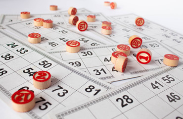 Bingo or lotto game. Wooden kegs of lotto on cards. Cards and chips for playing bingo on a white table