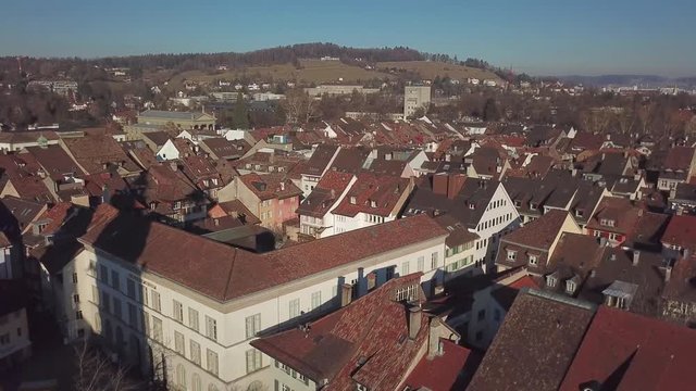 Drone flight with aerial view above church in old town of Winterthur in Switzerland. Tower and building roofs from above. Dynamic shots of European town.