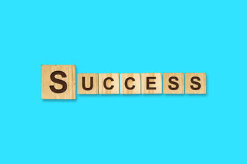 Success. Words written on a wooden block. Blue background. Isolated. Business concept.