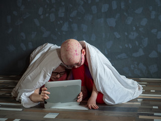 Caucasian children in pink t-shirt with smartphone on floor. Boys posing for camera under white...
