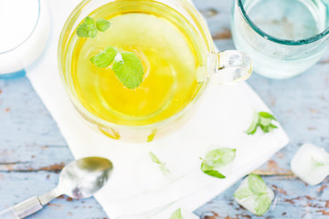Cold fresh mint leaf tea, mint tea with ice cubes in a glass cup on a wooden table, cold mint beverage, healthcare and healthy eating concept